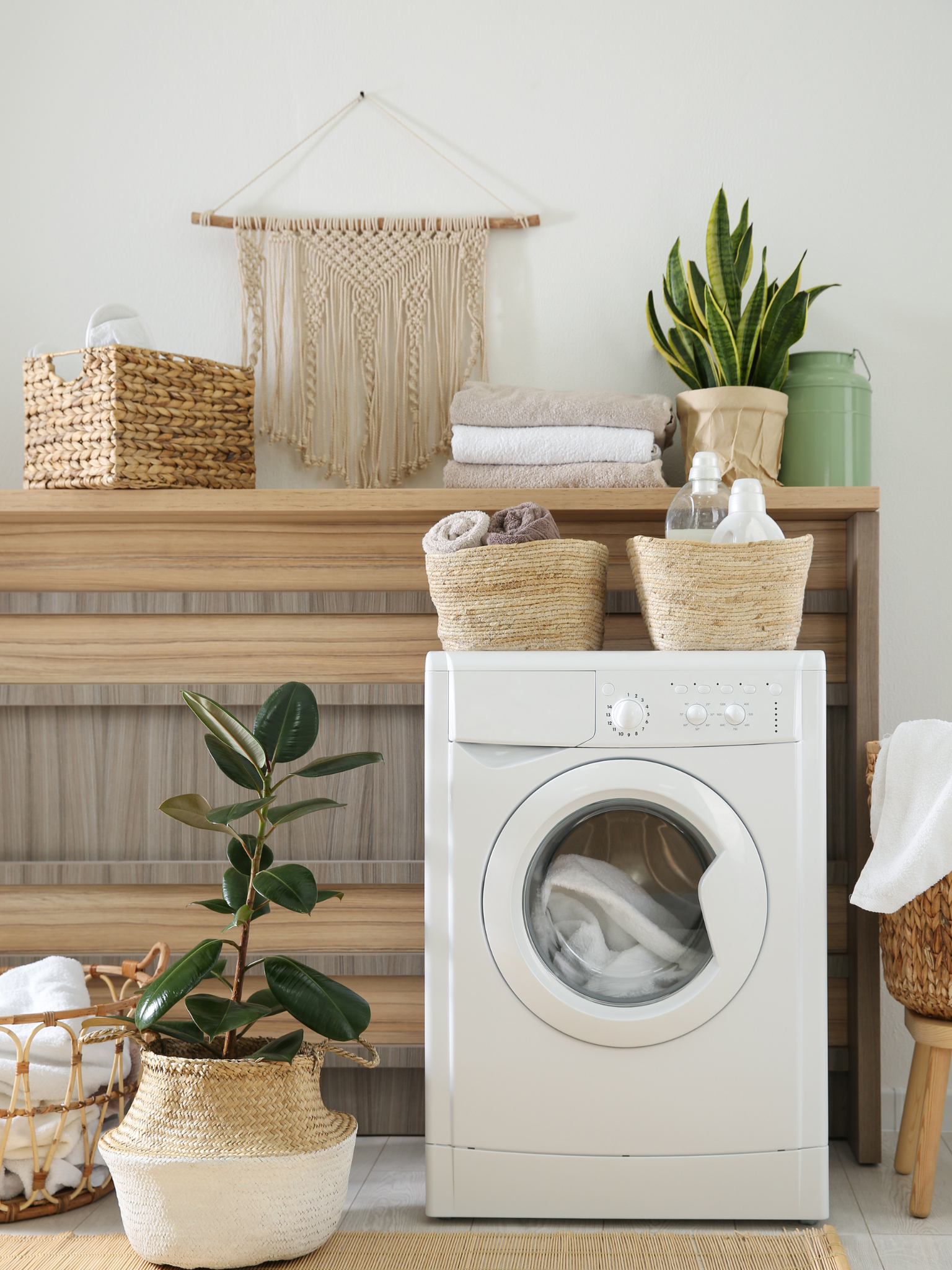 Laundry room with washing machine, baskets, and plants.