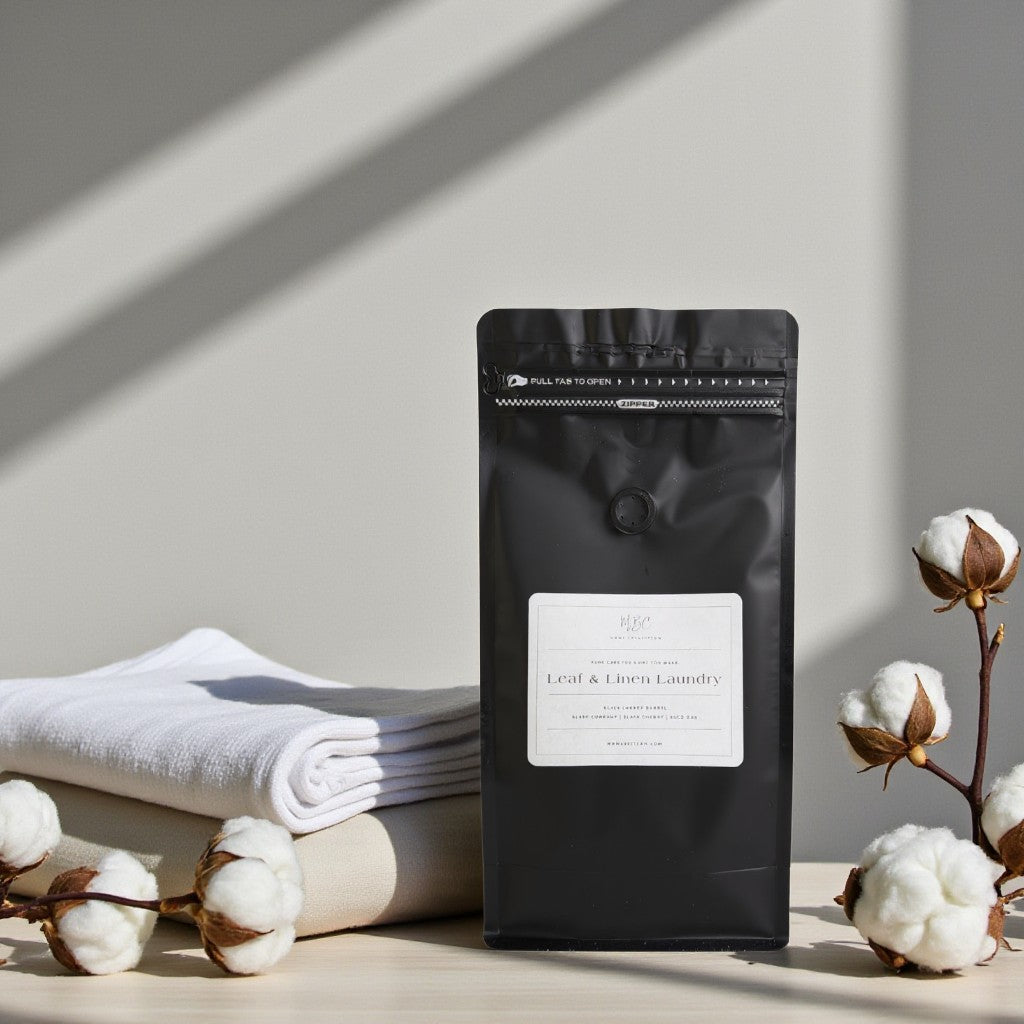Black coffee bag with a label on a light surface with white towels and cotton flowers.