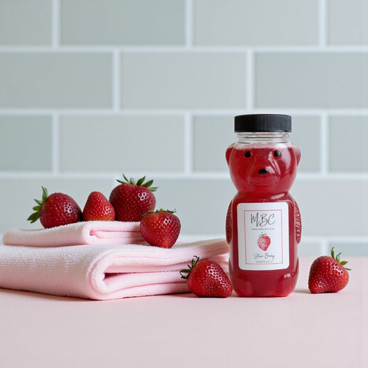 Bear shaped bubble bath bottle with strawberry scented bubble bath on a light pink surface with strawberries around