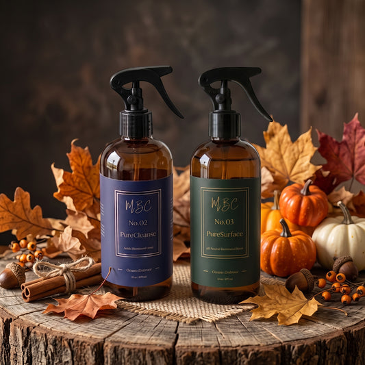 Mama Be Clean seasonal Surface Calibration Duo featuring Protocol No. 02 PureCleanse and Protocol No. 03 PureSurface in 16oz amber glass spray bottles set against a rustic fall display with leaves, pumpkins, and cinnamon sticks.